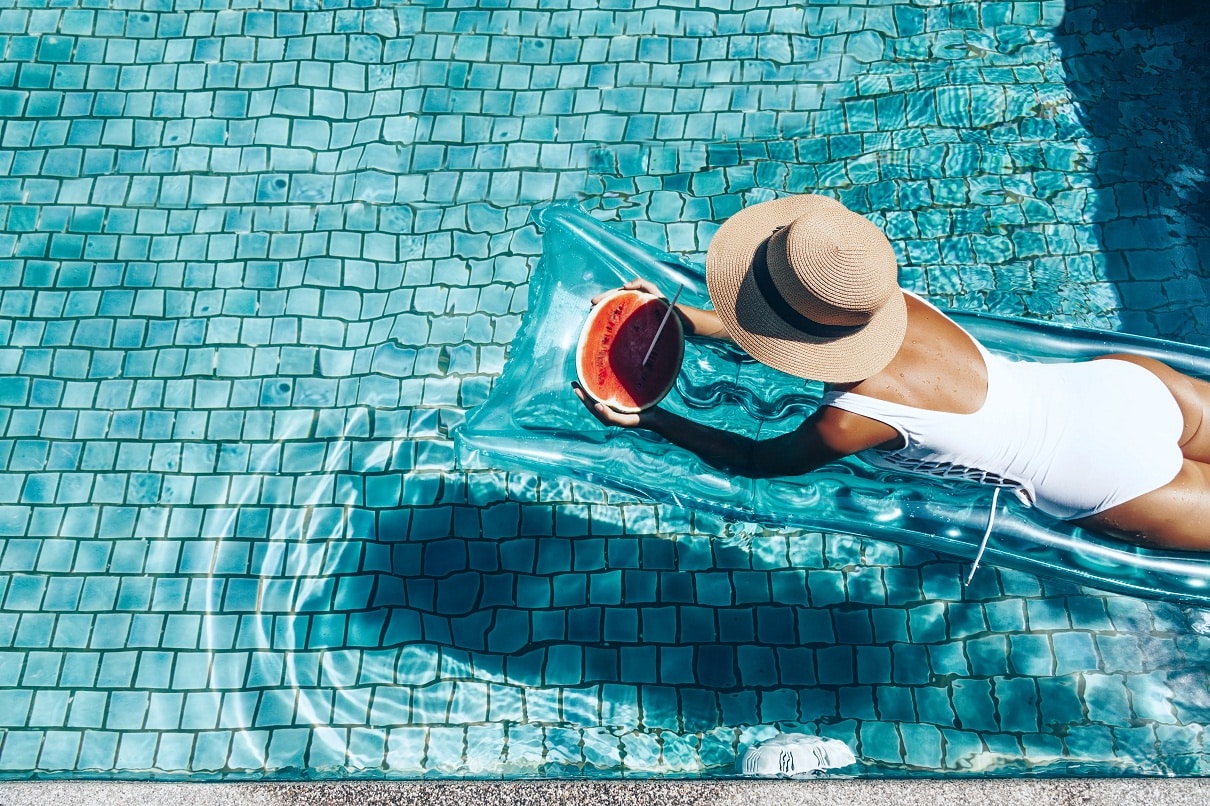 Woman sitting on a pool float in a Sunrise Pool eating watermelon