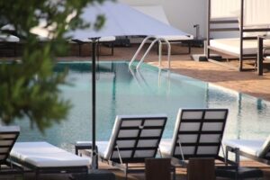 View of lounge chairs beside a pool on a sunny day.